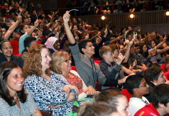 Students raising hands in auditorium 