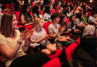 Students clapping in an auditorium 